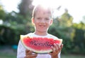 Little caucasian kid holding slice of watermelon in sunset