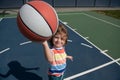 Little caucasian sports kid playing basketball holding ball with funy face.