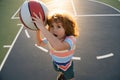 Little caucasian sports kid playing basketball holding ball with funy face.