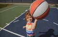 Little caucasian sports kid playing basketball holding ball with funy face.
