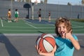 Little caucasian sports kid playing basketball holding ball with happy face. Thumbs up people.