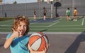 Little caucasian sports kid playing basketball holding ball with happy face. Thumbs up people.