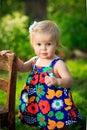 Little caucasian toddler stands using chair for support outside