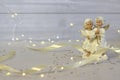 Little ceramic angels pray and sing songs, on a blurred background, satin ribbon and lights Royalty Free Stock Photo