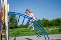 Little charming baby girl playing on a playground, riding on a swing on a bright sunny day Royalty Free Stock Photo