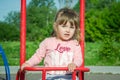 Little charming baby girl playing on a playground, riding on a swing on a bright sunny day Royalty Free Stock Photo