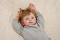 Little charming girl child, baby with pierced ears pierced on the bed in the morning when waking up and stretching raises his hand Royalty Free Stock Photo