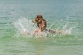 Little charming girl child bathes in a lake and plays splashing water Royalty Free Stock Photo