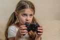 Little charming girl child plays a joystick in a video game on a game console