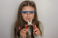 Little charming girl child in safety glasses with pliers