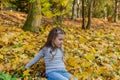 Little charming girl child throws up fallen yellow maple leaves in autumn park