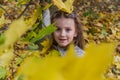 Little charming girl child throws up fallen yellow maple leaves in autumn park