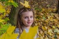 Little charming girl child throws up fallen yellow maple leaves in autumn park