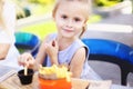 Little charming girl eating rench fries with sauce at street cafe outside. Royalty Free Stock Photo
