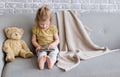 Little charming girl sits on a gray sofa.