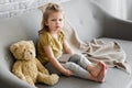 Little charming girl sits on a gray sofa.