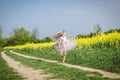 Little charming girl in summer dress running in rural path in green nature