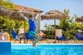 Little cheerful boy jumping to the pool and making water splash, enjoying time in the refreshing water Royalty Free Stock Photo