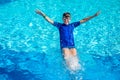 Little cheerful boy jumping to the pool and making water splash, enjoying time in the refreshing water Royalty Free Stock Photo