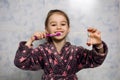 Little cheerful girl brushes her teeth with toothpaste with an hourglass timer Royalty Free Stock Photo