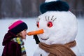 A little cheerful girl look at funny snowman face Royalty Free Stock Photo