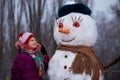 A little cheerful girl look at funny snowman face Royalty Free Stock Photo