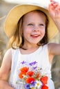 Little cheerful girl in a straw hat with wild flowers red poppy bouquet Royalty Free Stock Photo