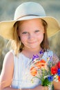 Little cheerful girl in a straw hat with wild flowers red poppy Royalty Free Stock Photo