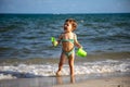 Little cheerful happy baby boy plays in the waves of the sea with a bucket and a shovel Royalty Free Stock Photo