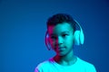 Little cheerful happy boy 6-7 years old wearing white t-shirt and headphones listen to music isolated on blue background Royalty Free Stock Photo