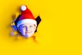 Little cheerful Santa in hat smiles, getting out of the ragged yellow background lit by neon light Royalty Free Stock Photo