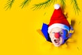 Little cheerful Santa in hat smiles, getting out of the ragged yellow background lit by neon light Royalty Free Stock Photo