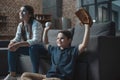 Little cheering boy with baseball mitt and ball sitting in living room with his mother and watching a game Royalty Free Stock Photo