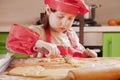 Little chef girl with cook hat and apron preparing sweet desert at home kitchen. Nutrition and education concept Royalty Free Stock Photo