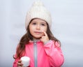 Little child applying cold cream to her face. Winter care.