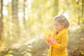 Little Child Baby Girl Caucasian Playing with Leaf,Autumn Nature background.Cute blonde blue-eyed girl in yellow knitted Royalty Free Stock Photo