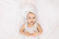 Little child baby girl having fun after bath with towel on head and face cream on cheeks, nose and forehead, lying on Royalty Free Stock Photo