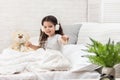 Little girl listening to the music with the headphones on bed. Royalty Free Stock Photo