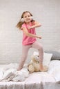 Little girl listening to the music with the headphones on bed. Royalty Free Stock Photo