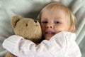 Little child in bed with teddy bear