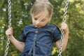 Little child blond girl having fun on a swing outdoor. Royalty Free Stock Photo