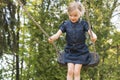 Little child blond girl having fun on a swing outdoor. Royalty Free Stock Photo