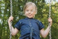 Little child blond girl having fun on a swing outdoor. Royalty Free Stock Photo