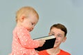 Little child with a book in his hands. The girl does not know how to read and holds a book, and the older brother watches on it