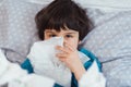 Little child boy blow his nose. Sick child with napkin in bed. Allergic kid, flu season. Kid with cold rhinitis, get cold Royalty Free Stock Photo