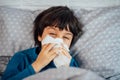 Little child boy blowing his nose. Sick child with napkin in bed Royalty Free Stock Photo