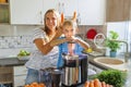 Little child boy with mother makes fresh carrot juice with juicer in kitchen Royalty Free Stock Photo