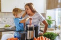 Little child boy with mother makes fresh carrot juice with juicer in kitchen Royalty Free Stock Photo