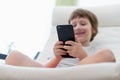 Little child boy playing online game, watching video on smartphone, sitting on couch entertaining in living room. Small kid using Royalty Free Stock Photo