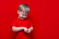 Little child boy pours pills from the can into the hand,healthy concept. It is dangerous tablets in babies hands red background